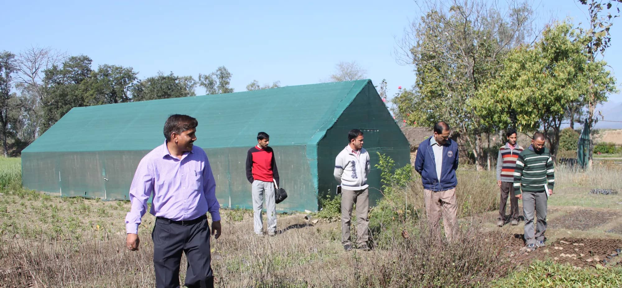 A group walking through the nursery beside a green shade-net house